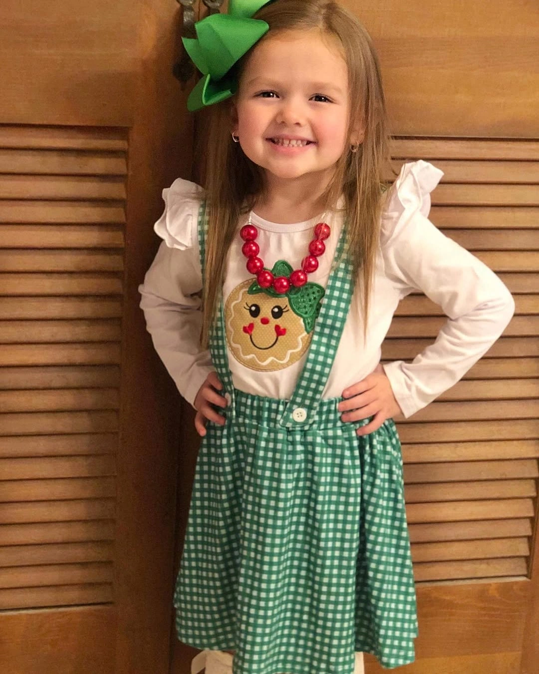 Child in green gingham jumper with gingerbread motif accessories