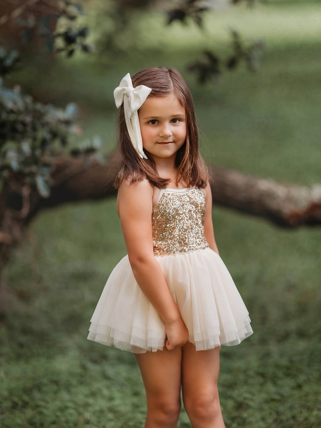 Child wearing gold bodice white layered dress and bow