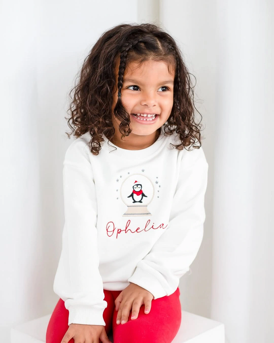 Child in white penguin sweatshirt with bright red pants