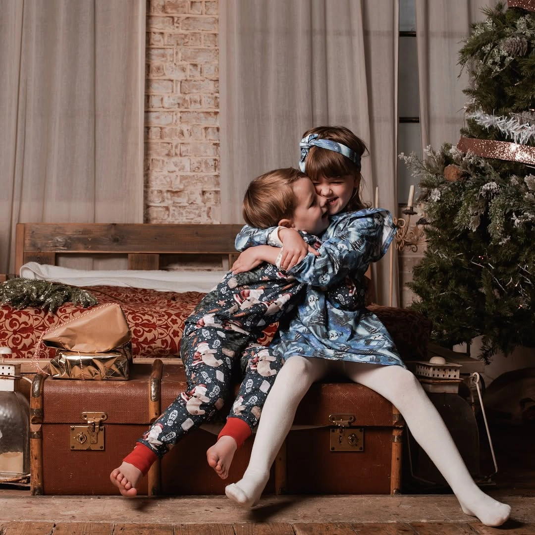 Two children wearing coordinated patterned Christmas pajama sets