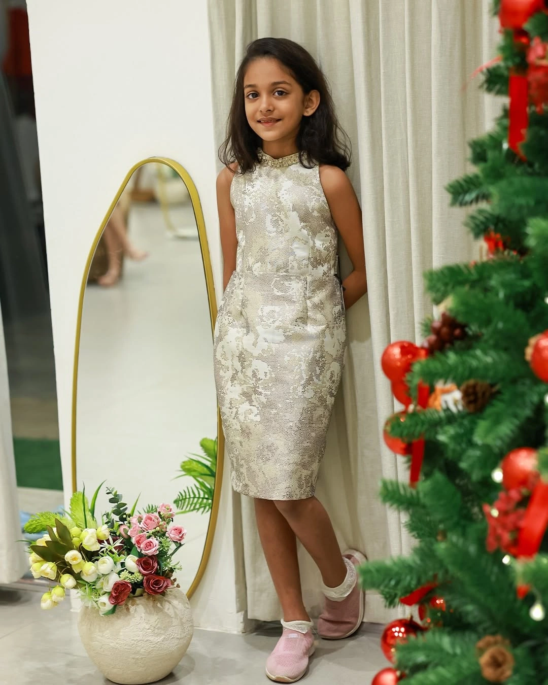 Child in white silver patterned dress with pink shoes