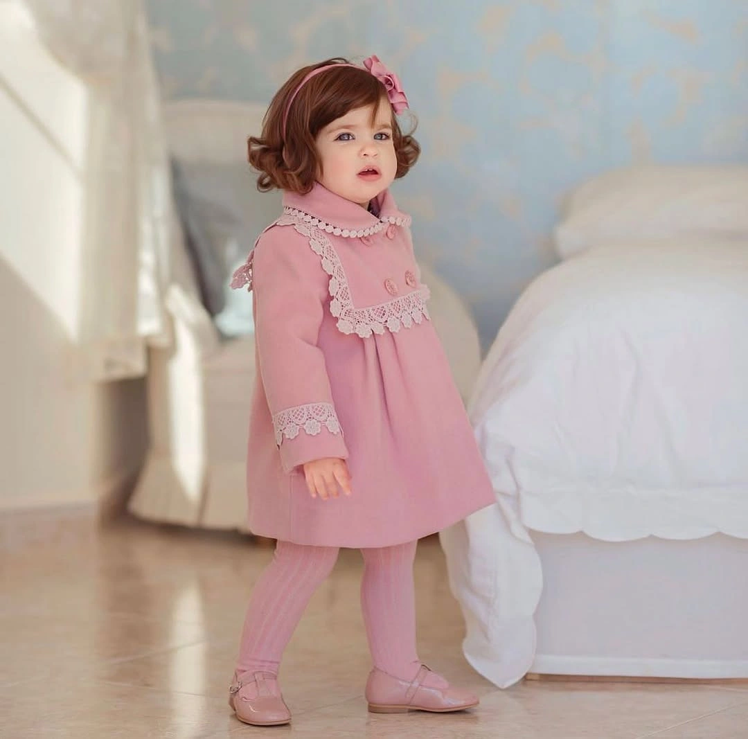 Child in pink long sleeve dress with decorative white trim