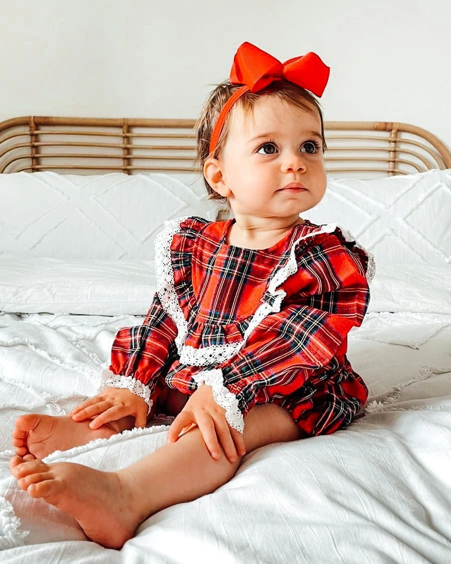 Baby wearing red plaid outfit with oversized red bow