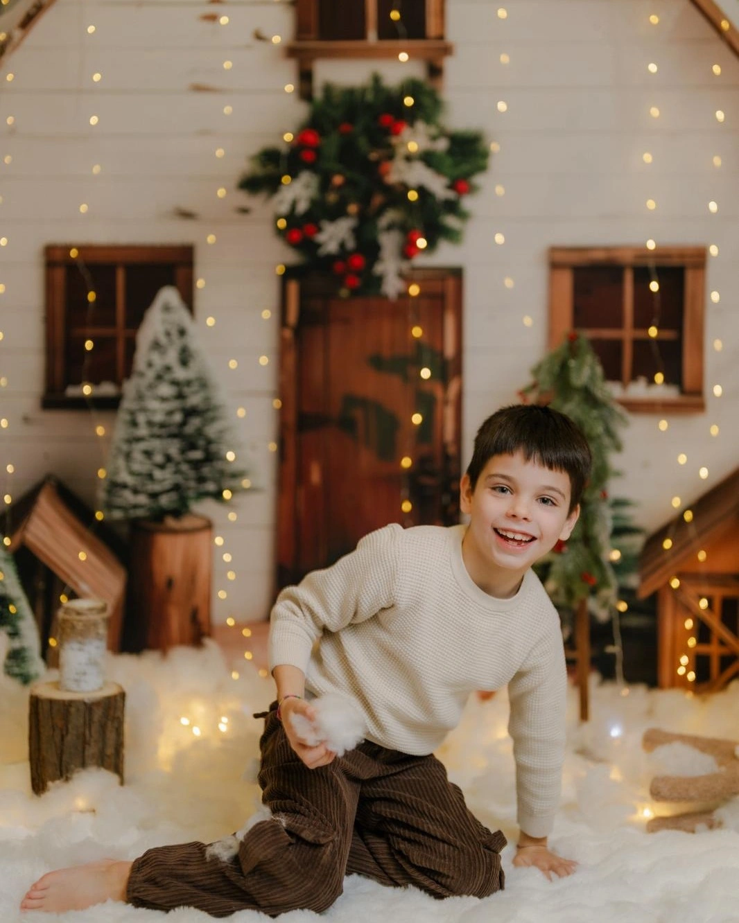 Child in cream sweater and brown pants in festive room