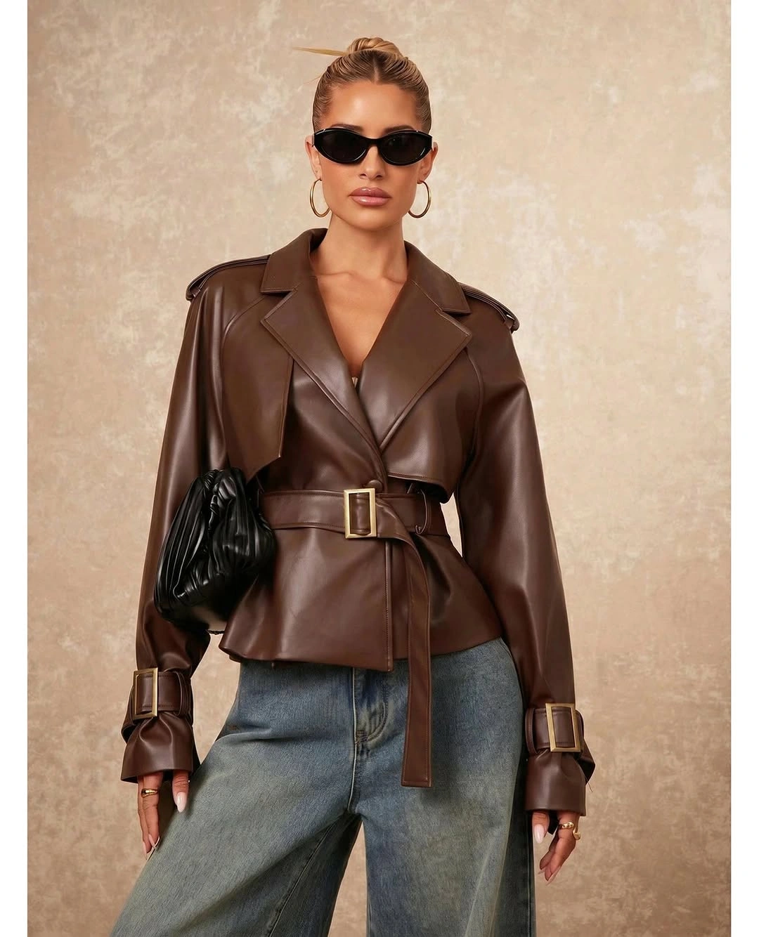 Brown belted leather-like jacket with wide jeans and clutch