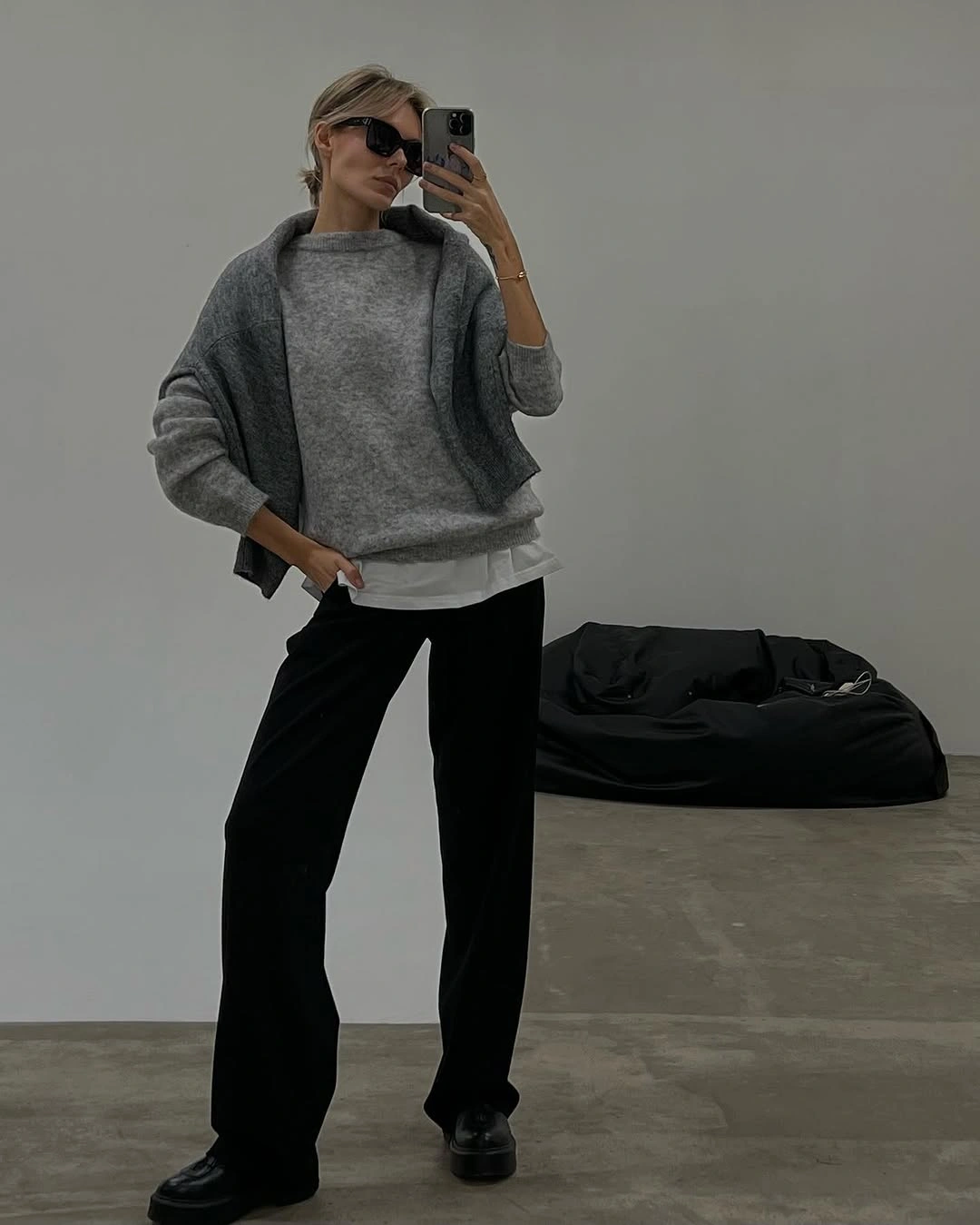 Gray oversized knit with white underlayer and black trousers