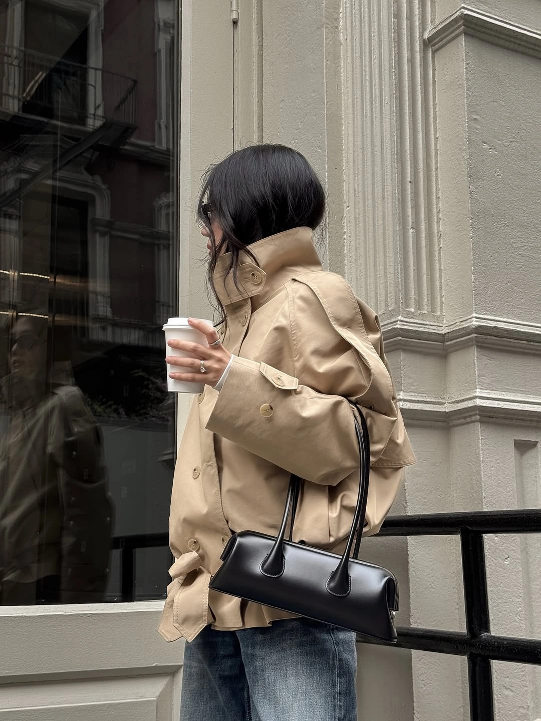 Beige short jacket with blue jeans and black handbag