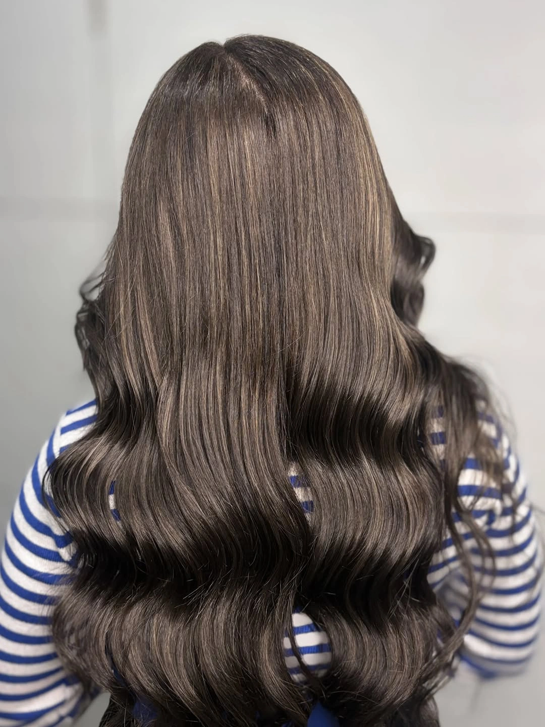 Long cool dark brown hair styled in broad back-view waves.