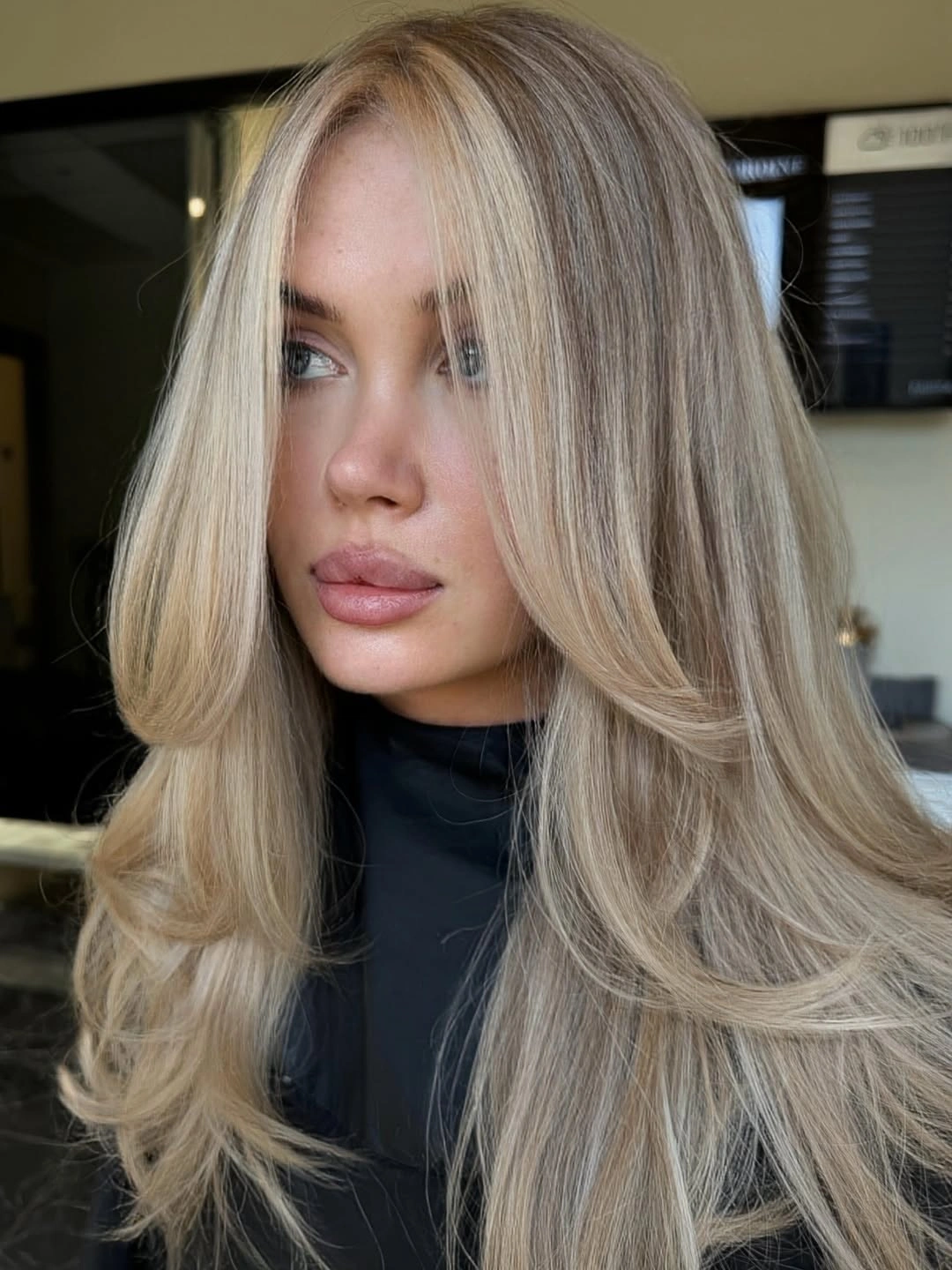 Long beige-blonde hair with soft front curves and neutral tonal depth.
