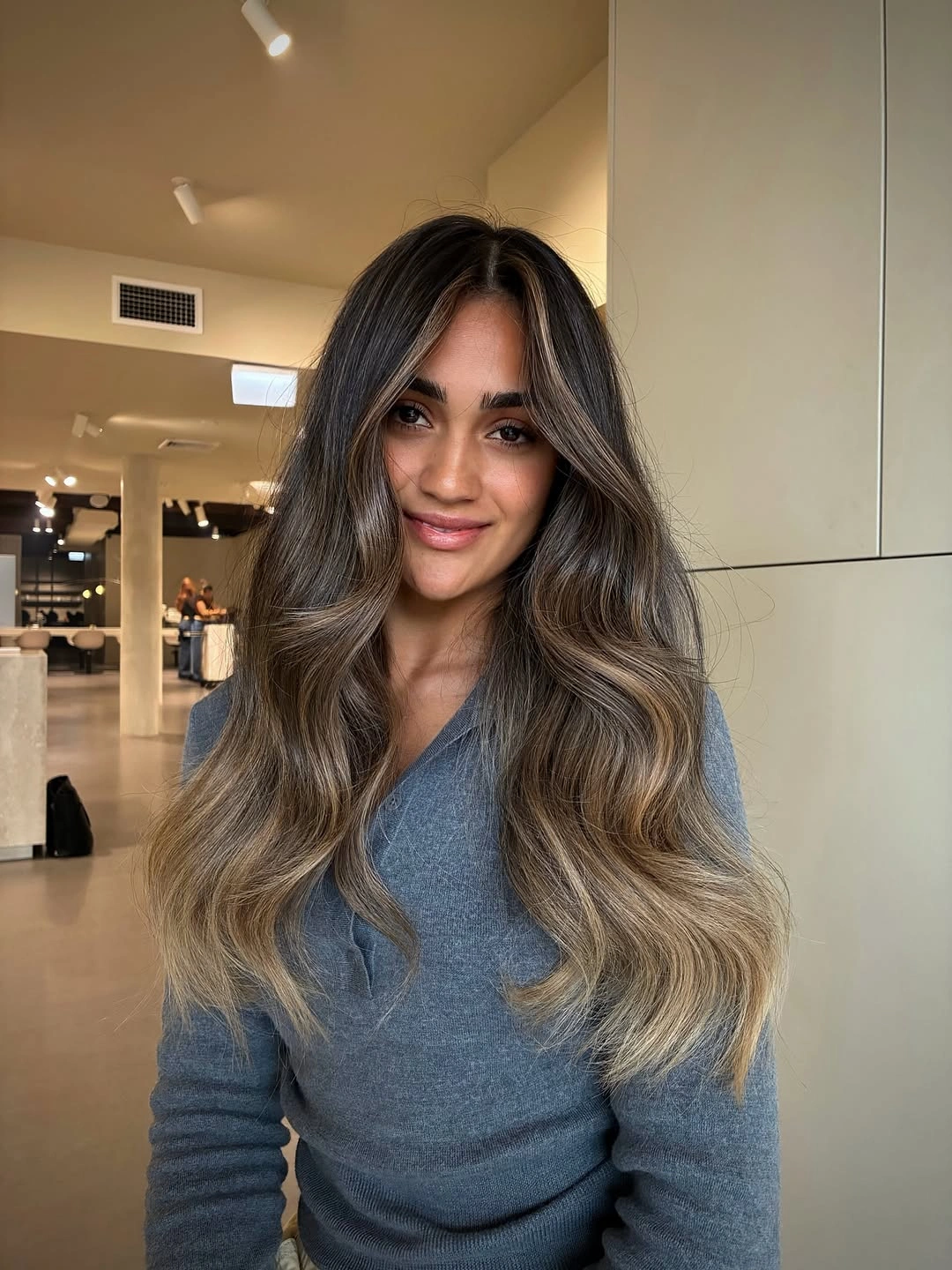 Long dark brunette hair with lighter beige sections and loose waves.