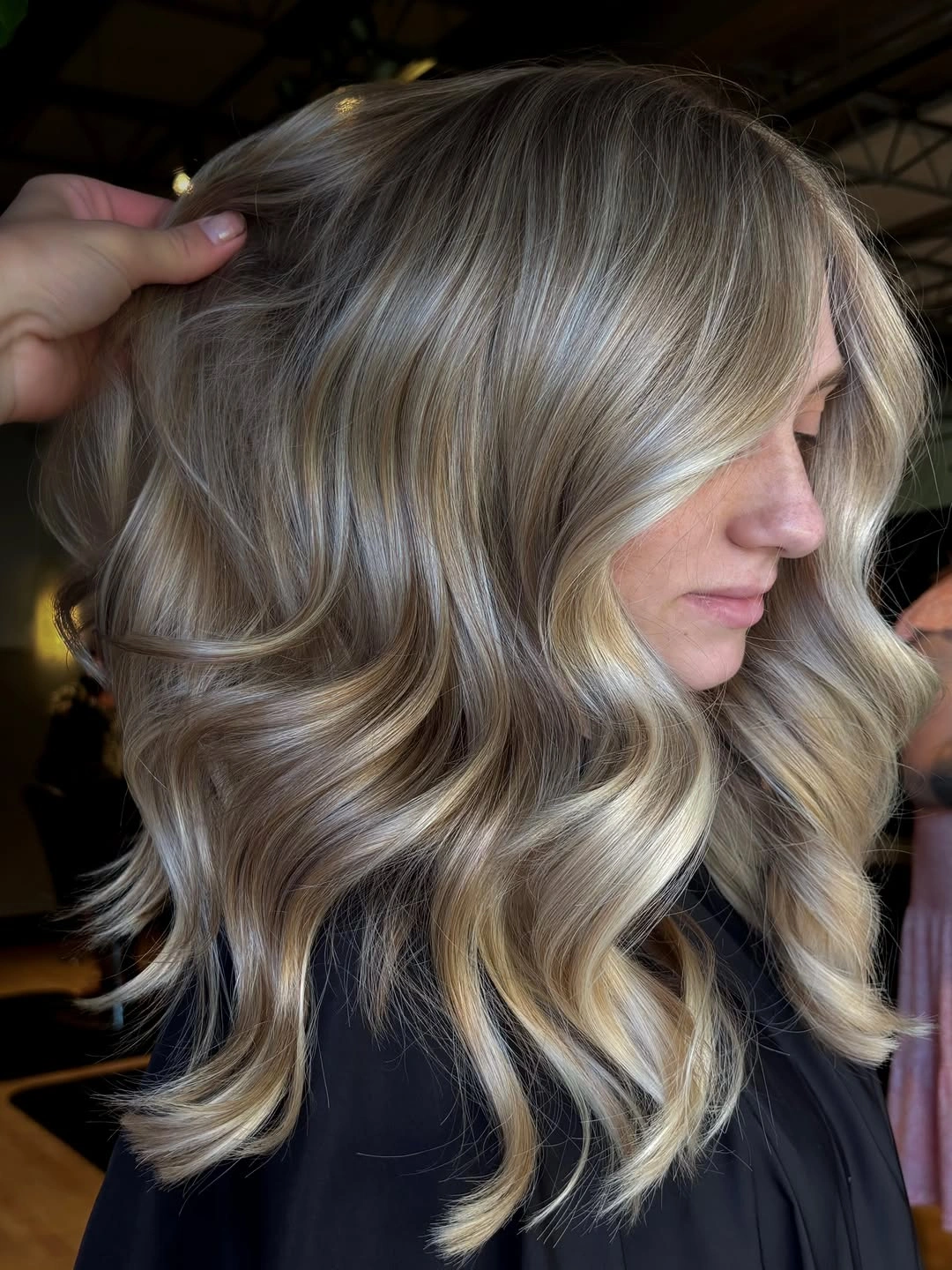 Medium ash-blonde hair with gray-beige tones and broad side-view waves.