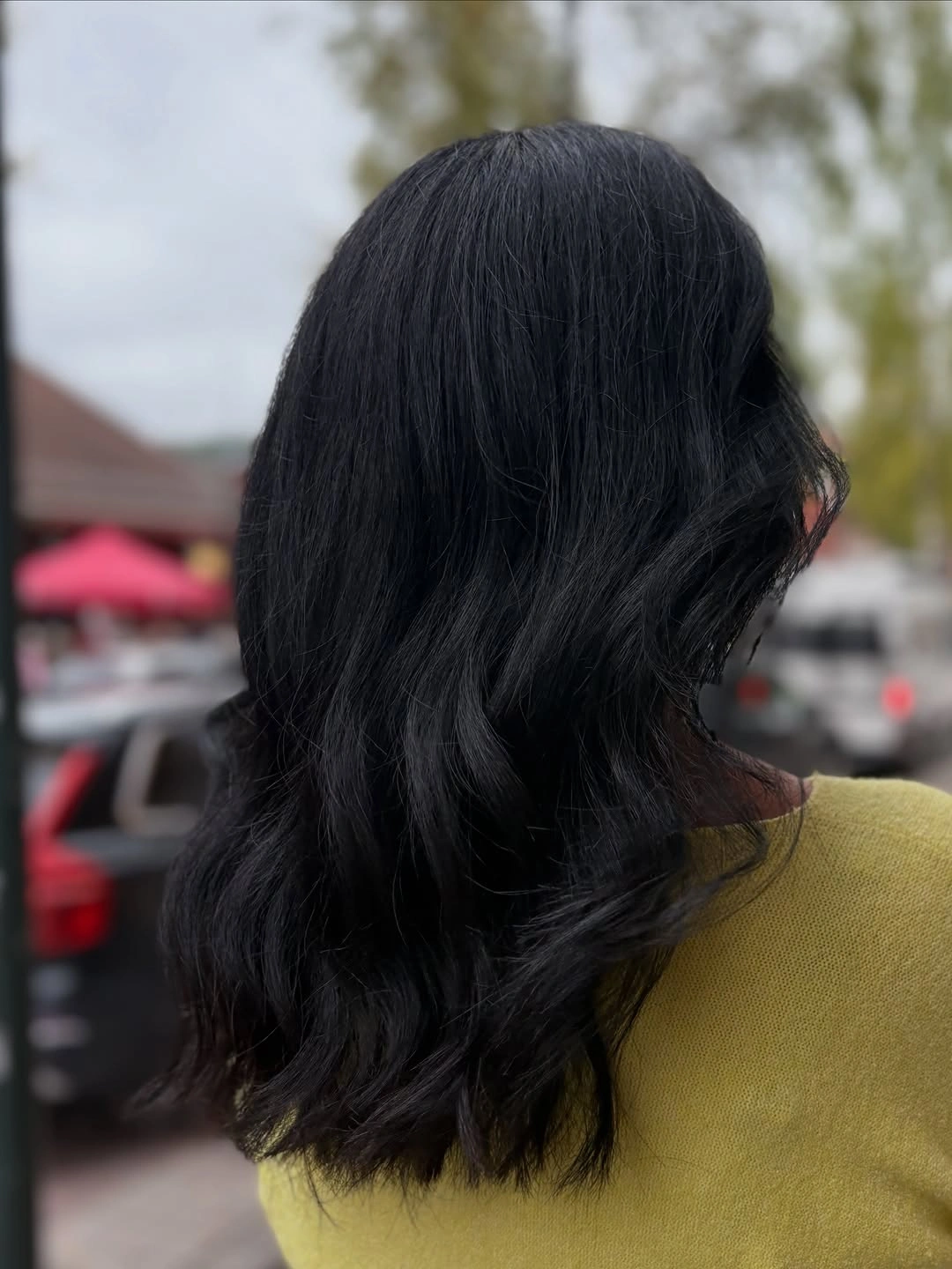 Long near-black hair with loose waves in a side-back view.