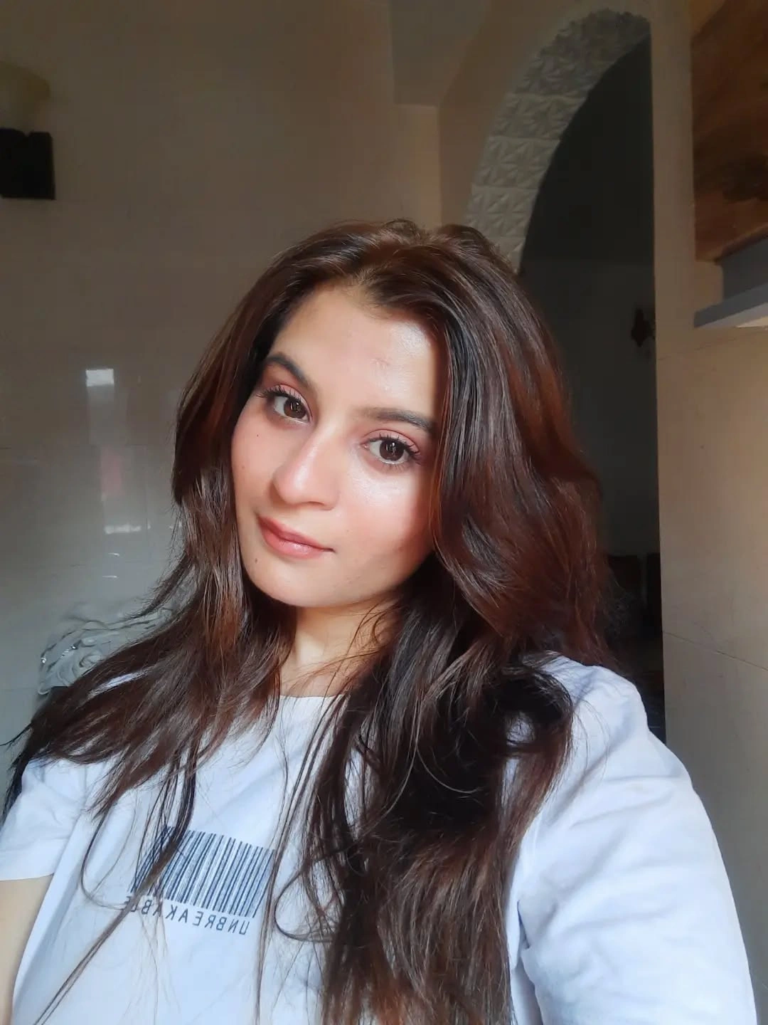 Long warm brown hair with soft front framing and subtle movement.