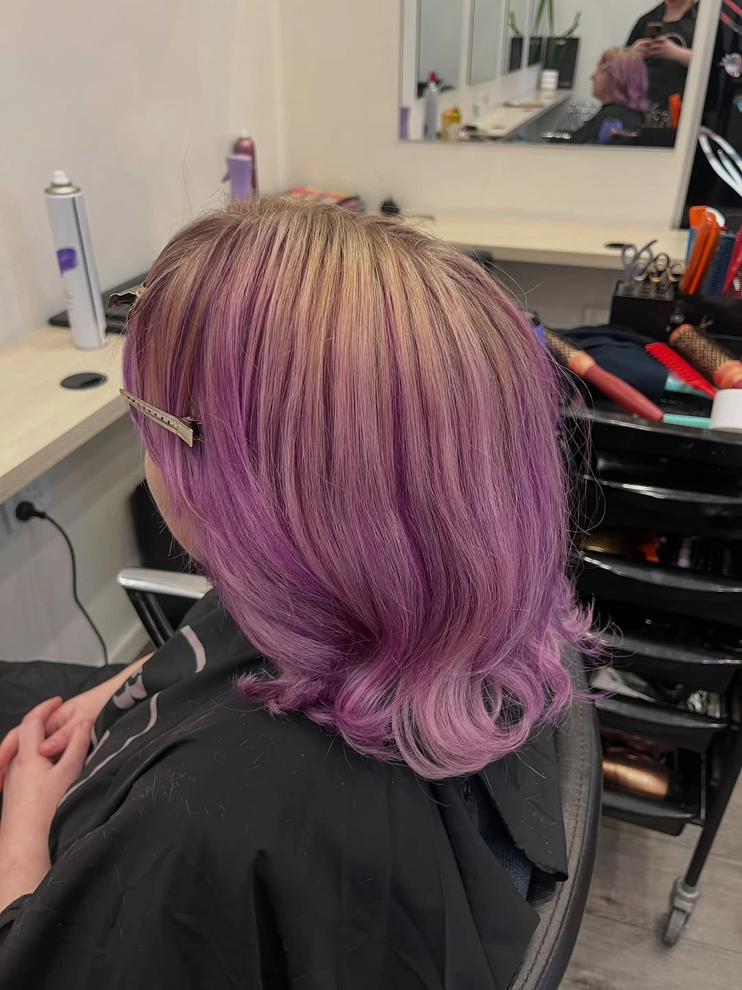 Short mauve-lavender hair with lighter sections and outward-curved ends.