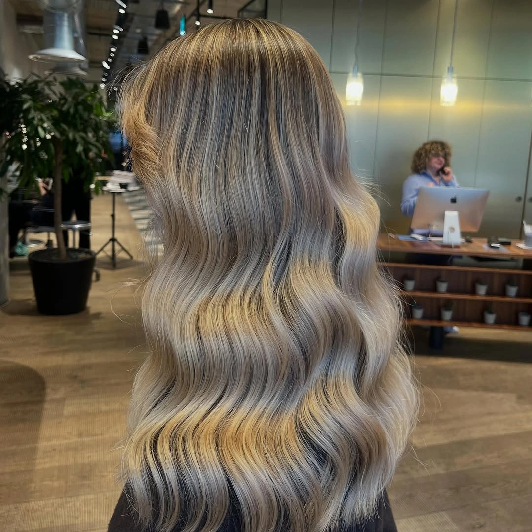 Long gray-beige blonde hair styled in repeated smooth back-view waves.