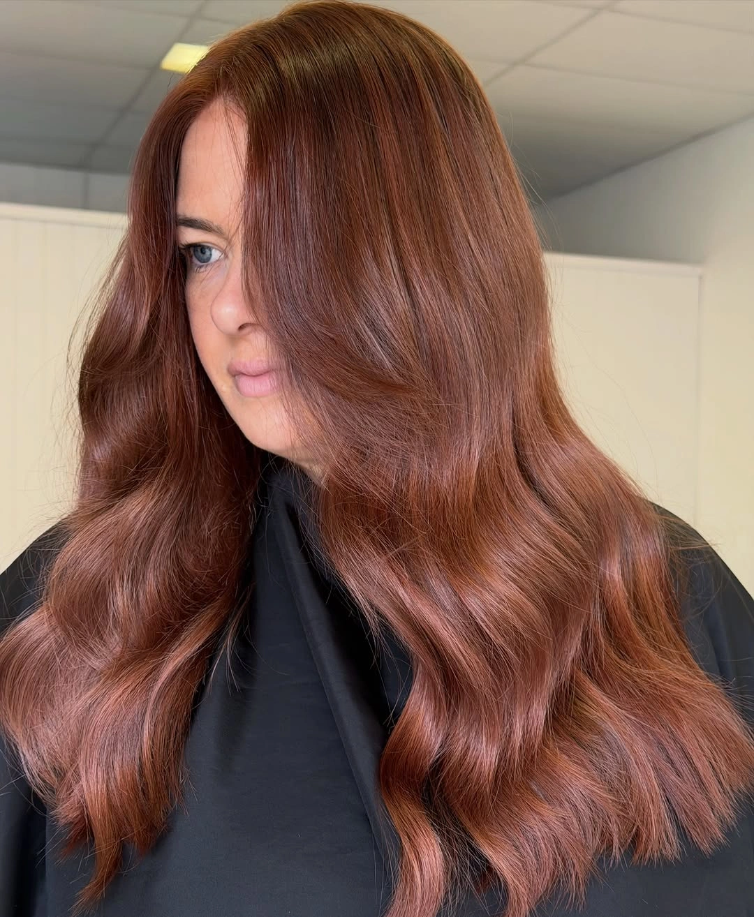 Long copper-auburn hair styled in broad warm-toned waves.