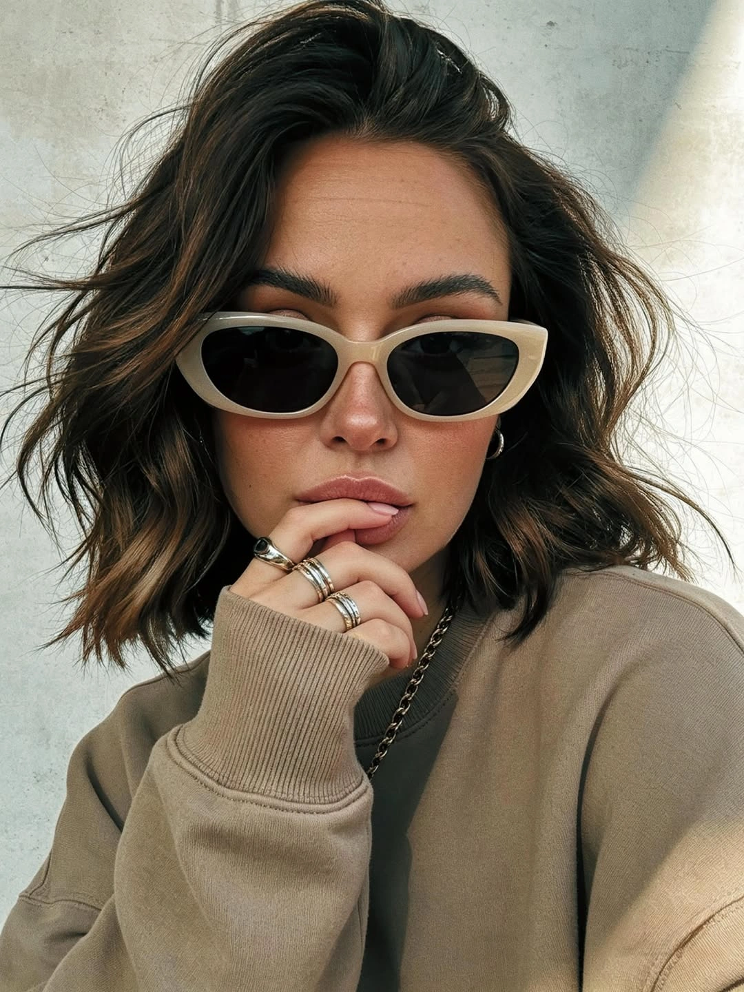 Dark shoulder-length wavy hair with sunglasses and a compact outline