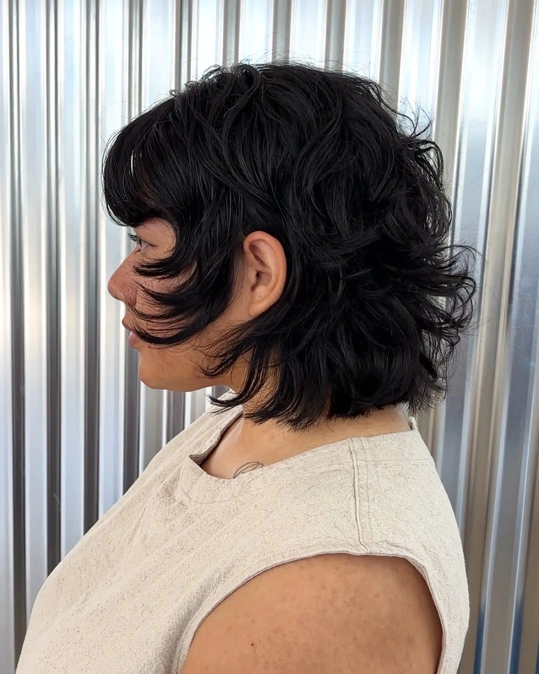 Dark shag-like short hair with waves and longer nape pieces