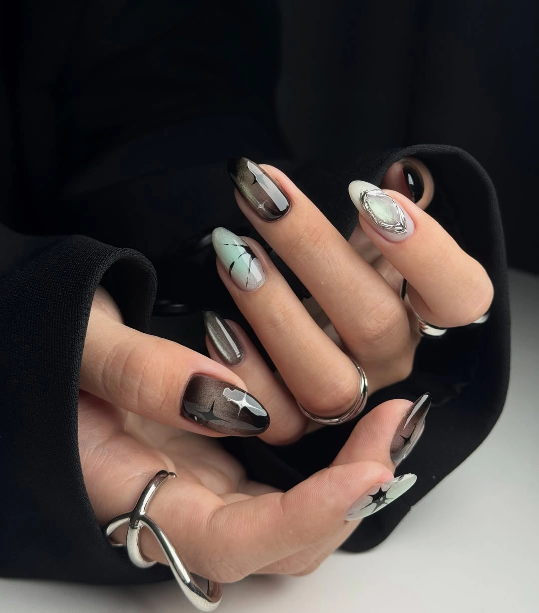 Almond nails with smoky black, mint, white and silver-looking accents