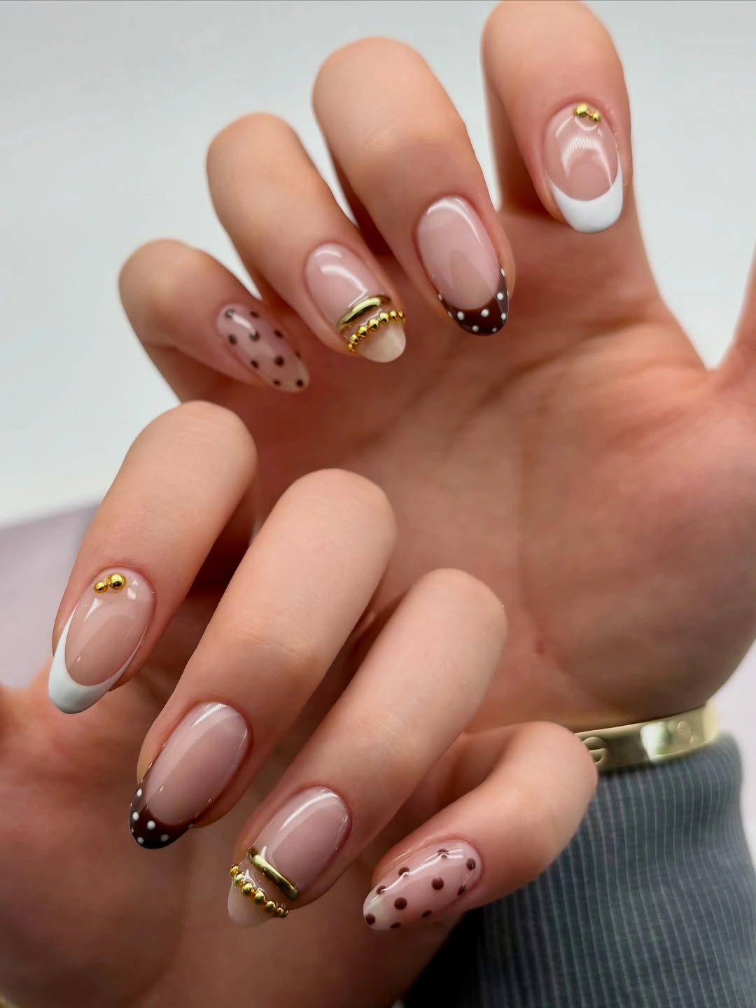 Short nude nails with white tips, brown edges and gold-colored bands