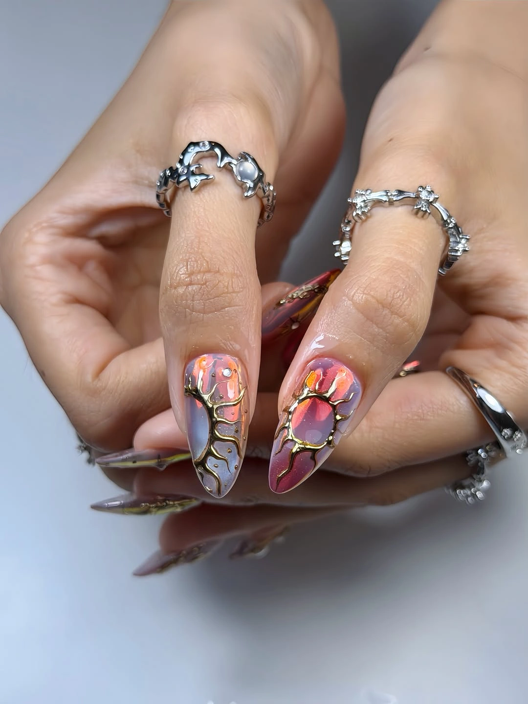 Pointed nails with orange, pink, gray and gold-colored abstract sections