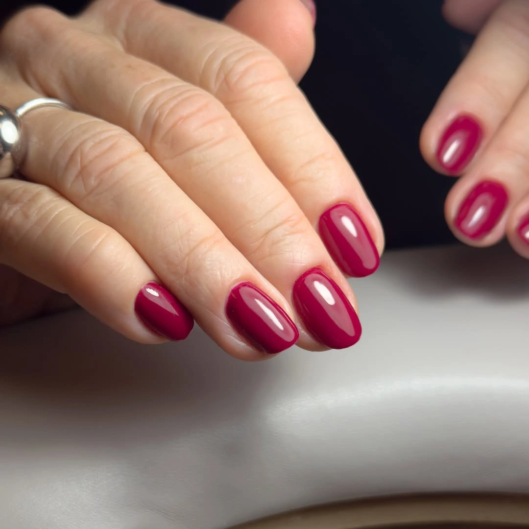 Short rounded nails with glossy berry magenta polish