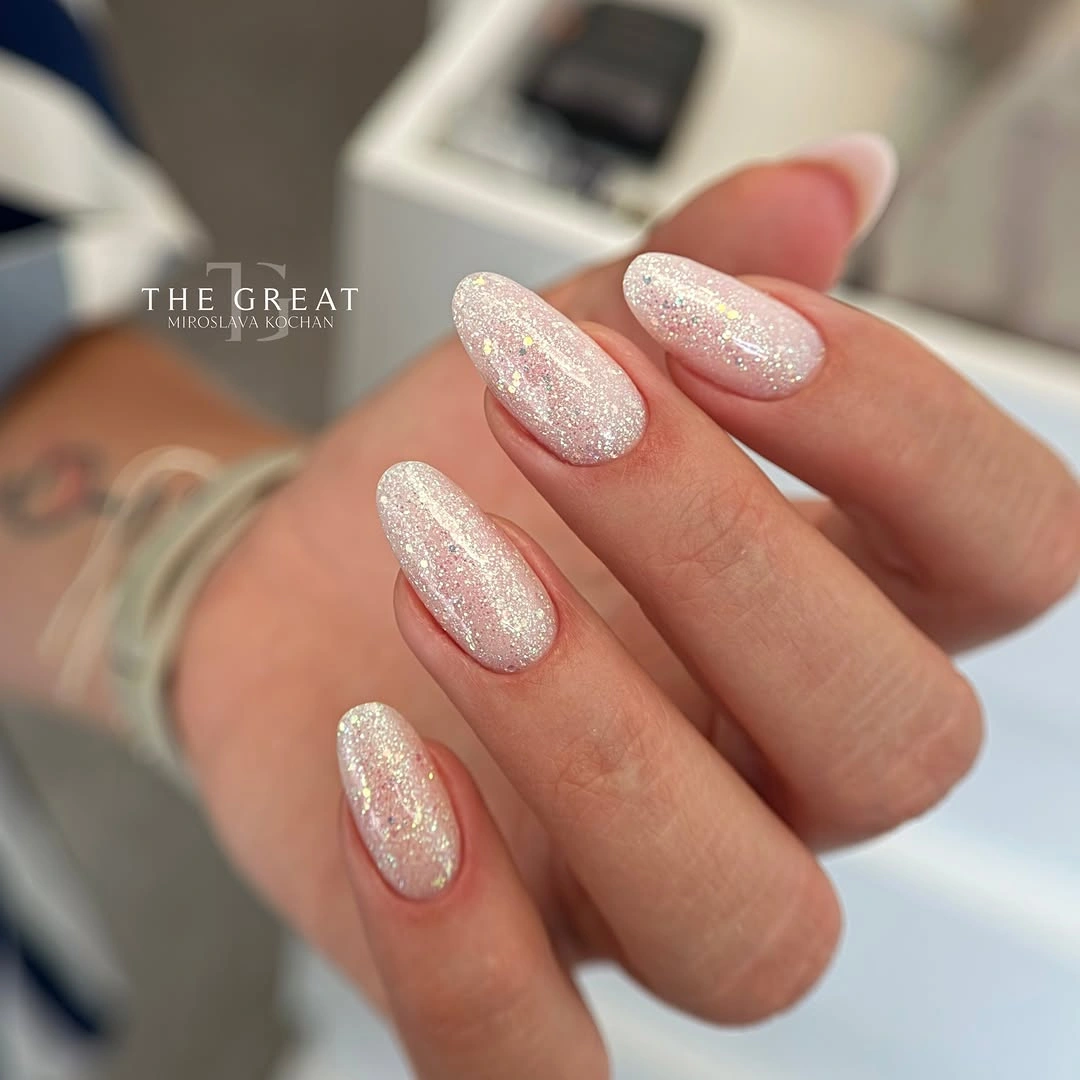Pale almond nails with dense fine sparkle and reflective shine