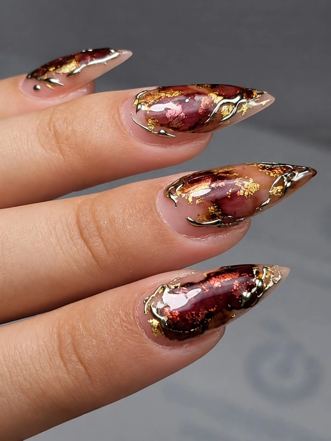 Pointed nails with amber brown shine and gold-colored outlines