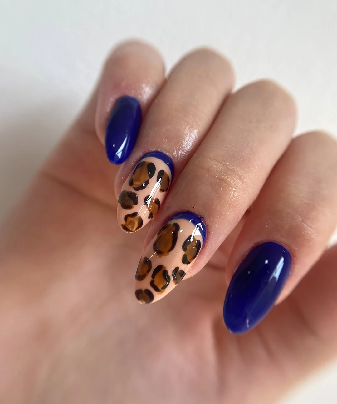 Almond nails with cobalt blue polish and leopard-like spotted accents