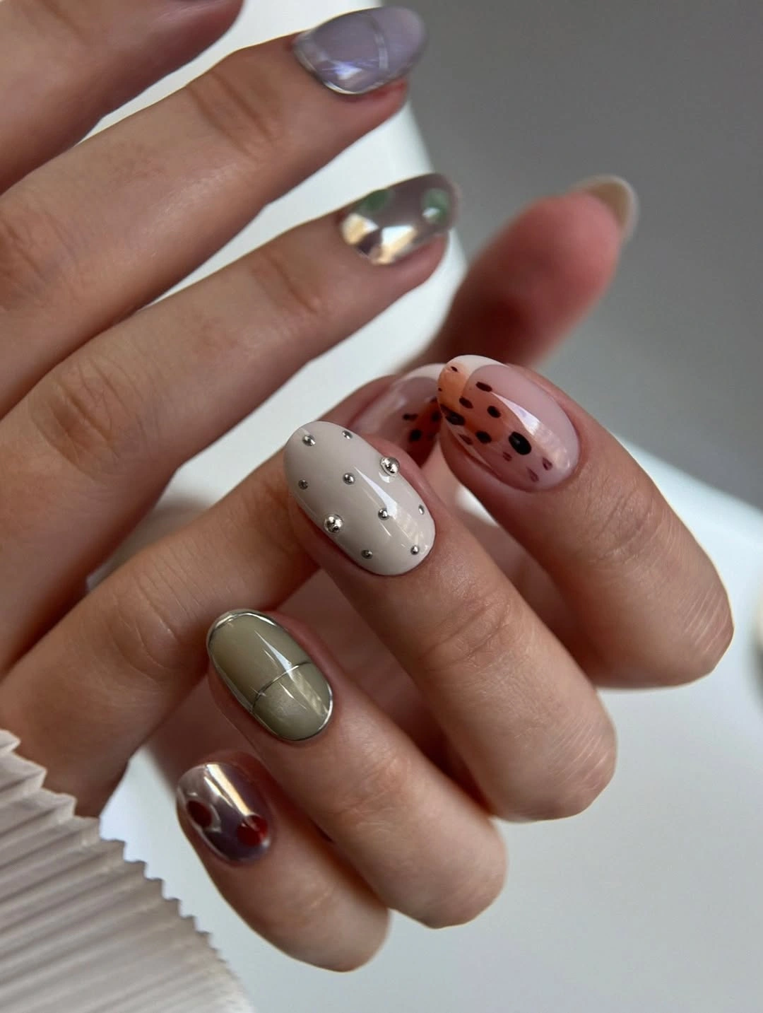 Short rounded nails with sage grid, silver dots and sheer black dots