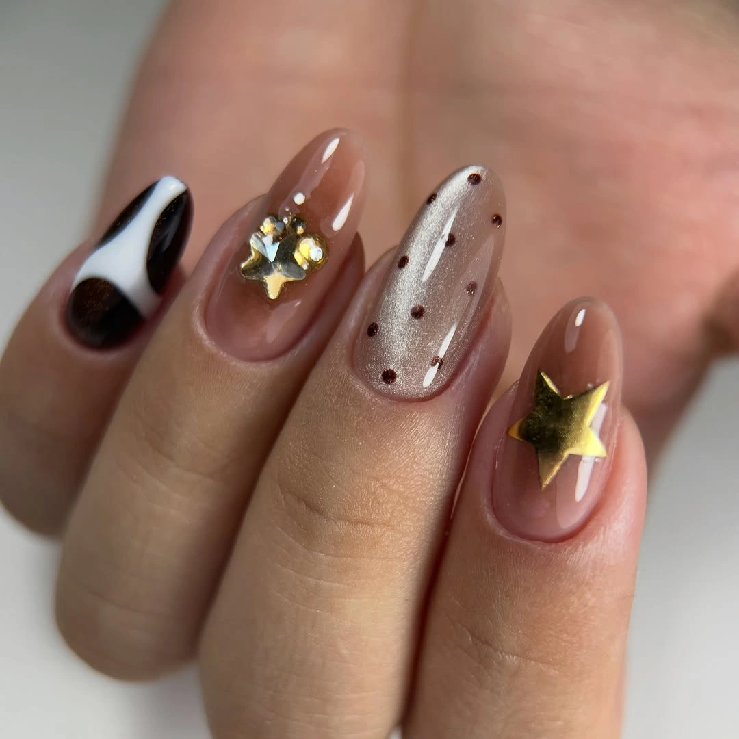 Nude almond nails with gold-colored stars and dotted shimmer