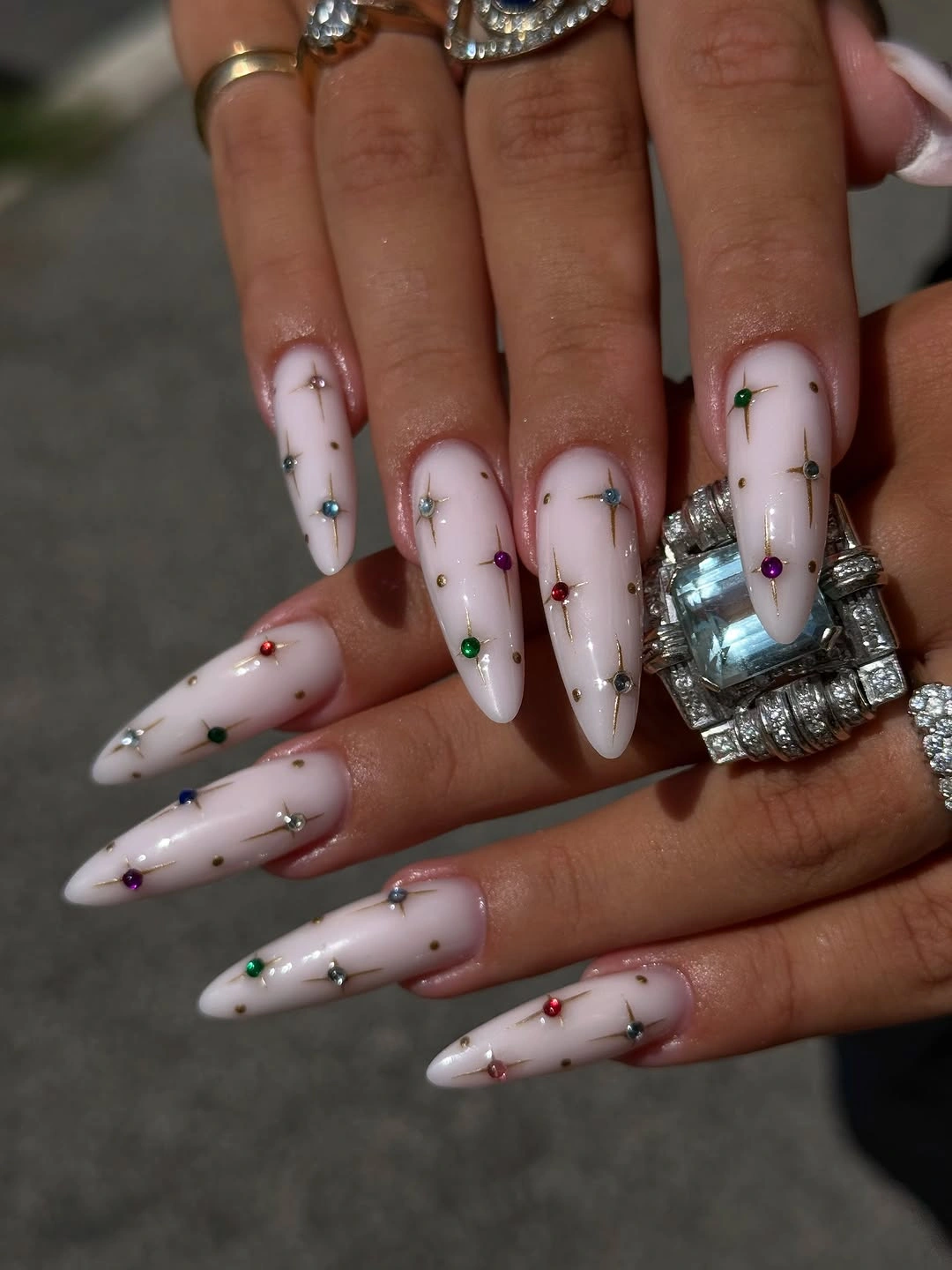 Pale pink almond nails with tiny multicolored dot accents