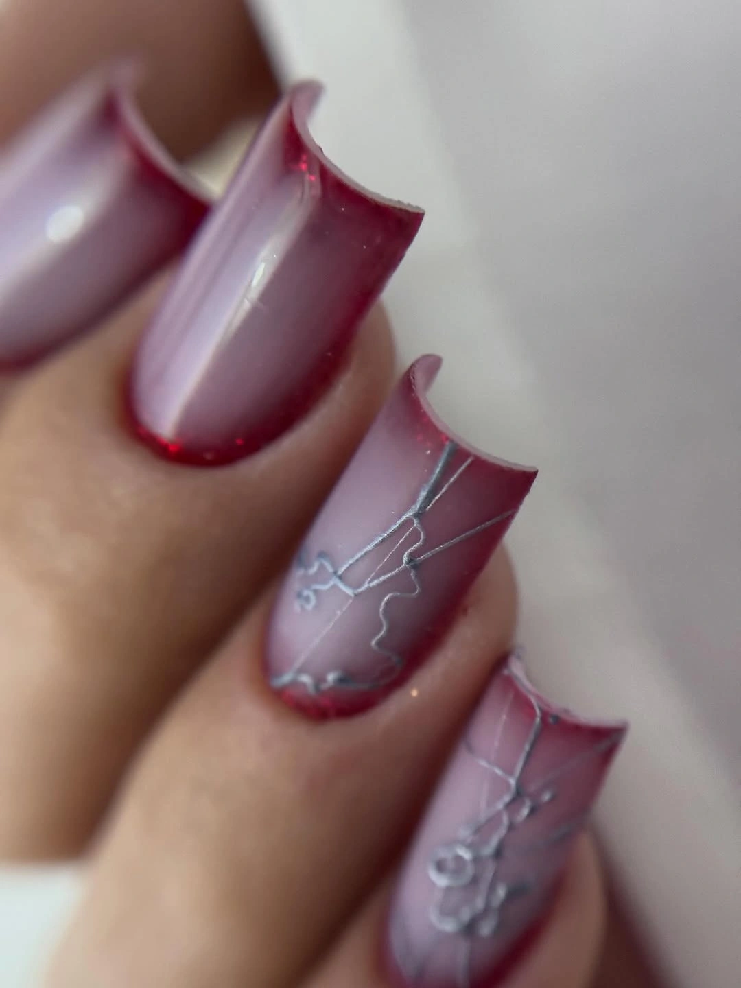 Short translucent red nails with spaced dots and deeper red patches