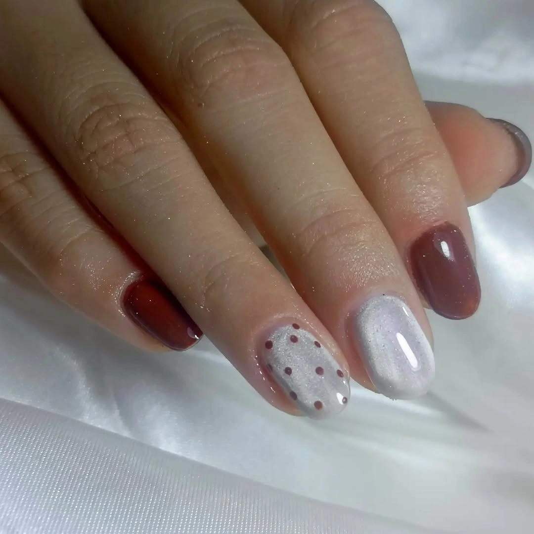 Short rounded nails with muted colors, metallic dots, and silver outlines