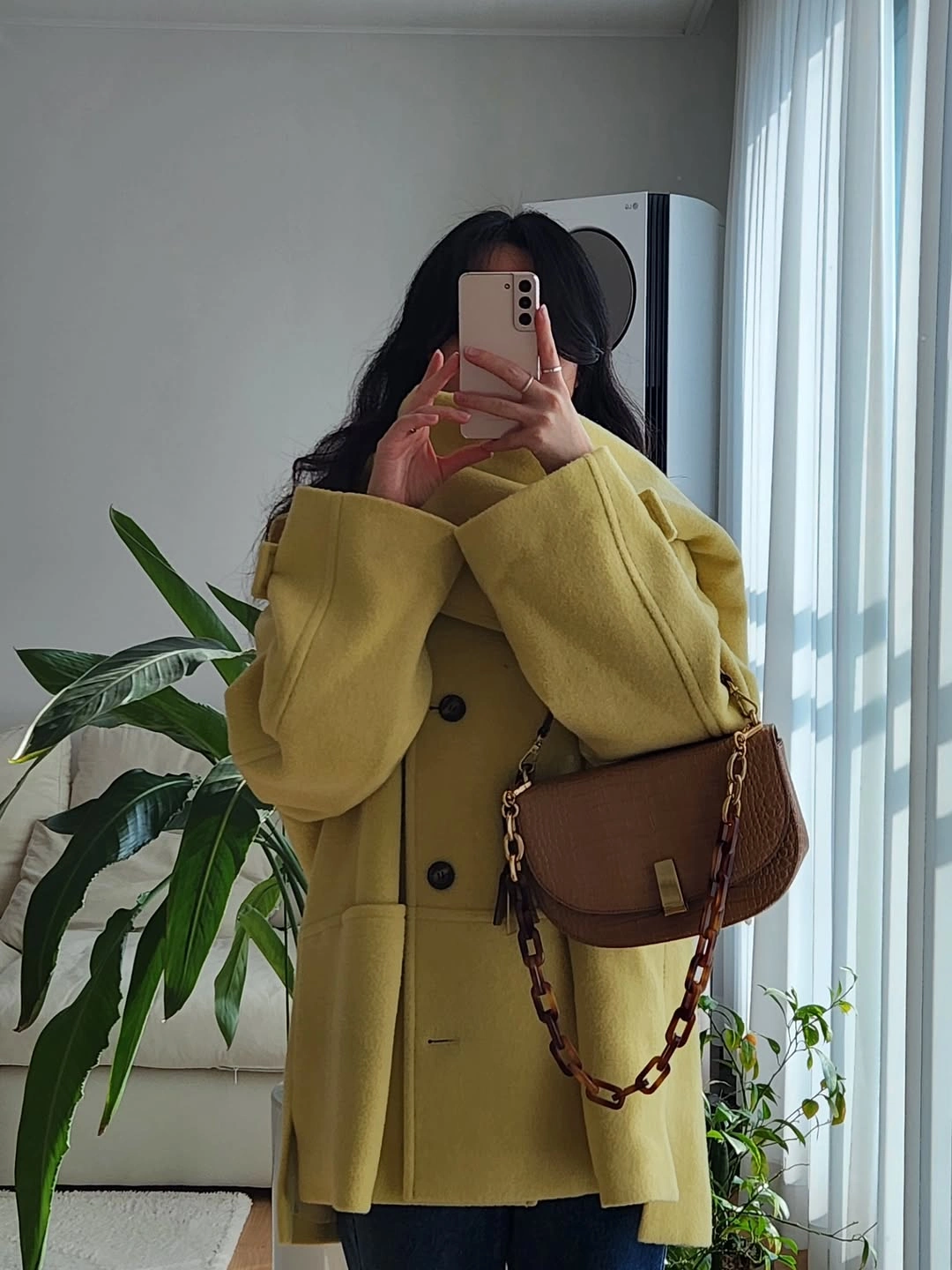 Yellow green coat with dark buttons and brown shoulder bag