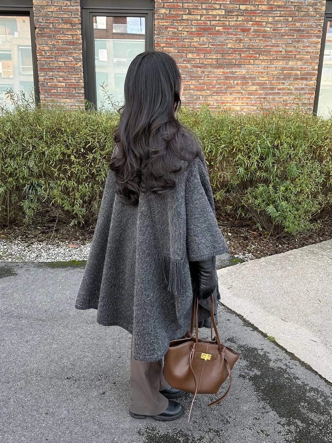 Gray cape-like outer layer with scarf, wide pants and brown handbag