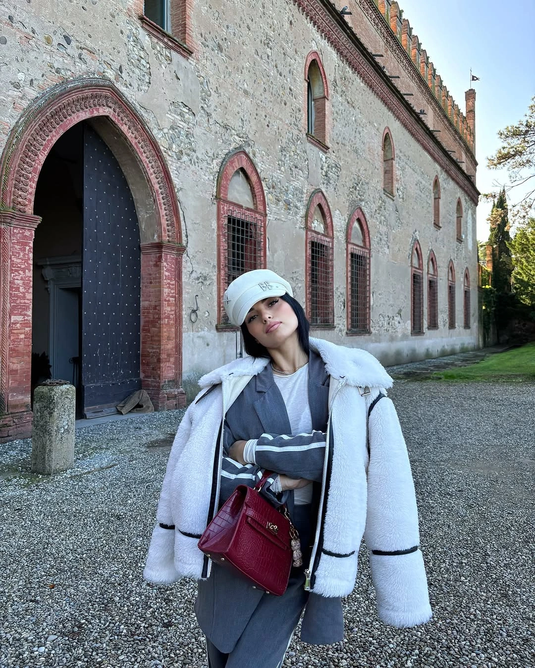 White plush-looking jacket with gray layers, cap and burgundy bag