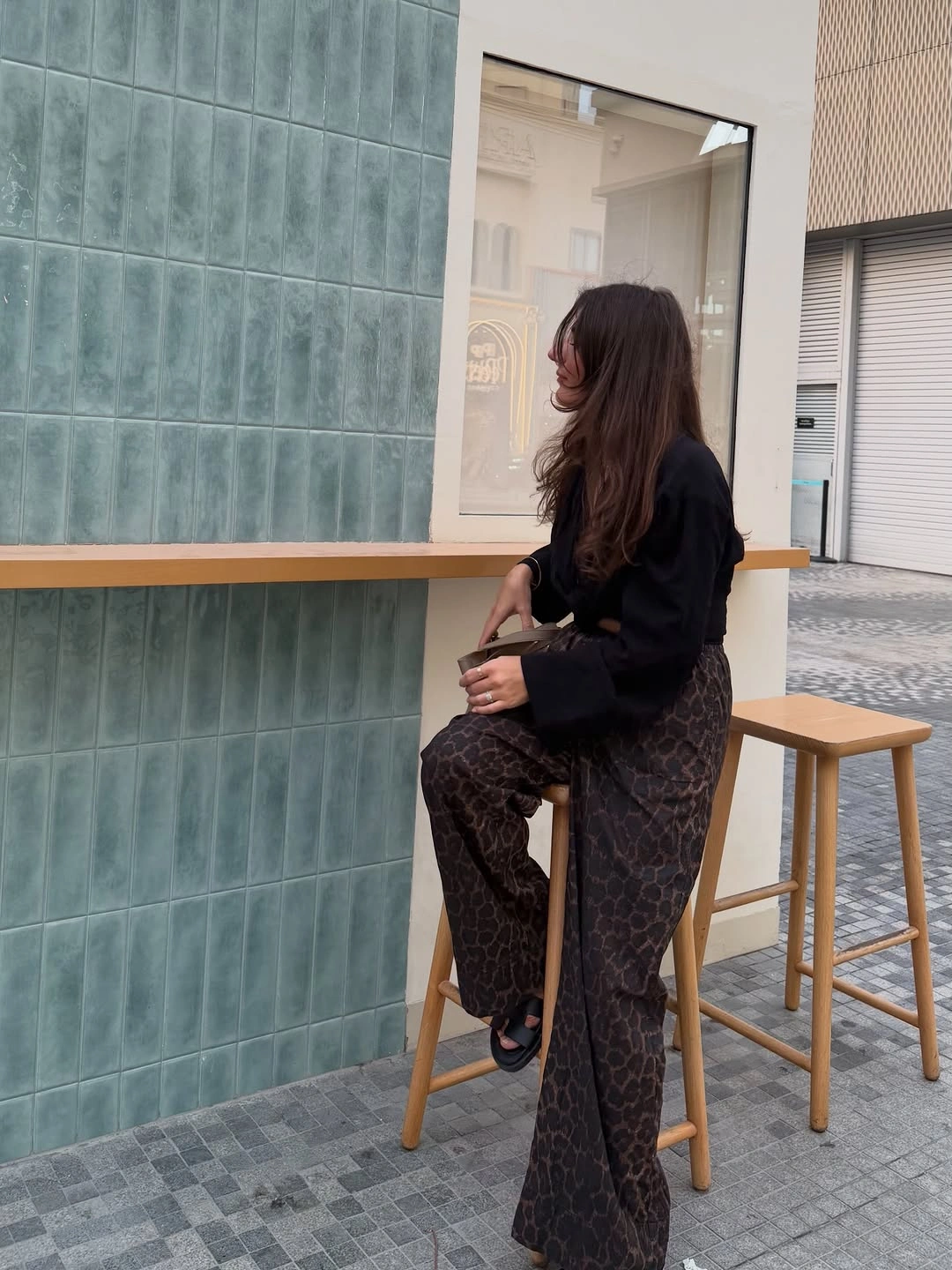 Black long-sleeve top with leopard-like flared pants and black shoes