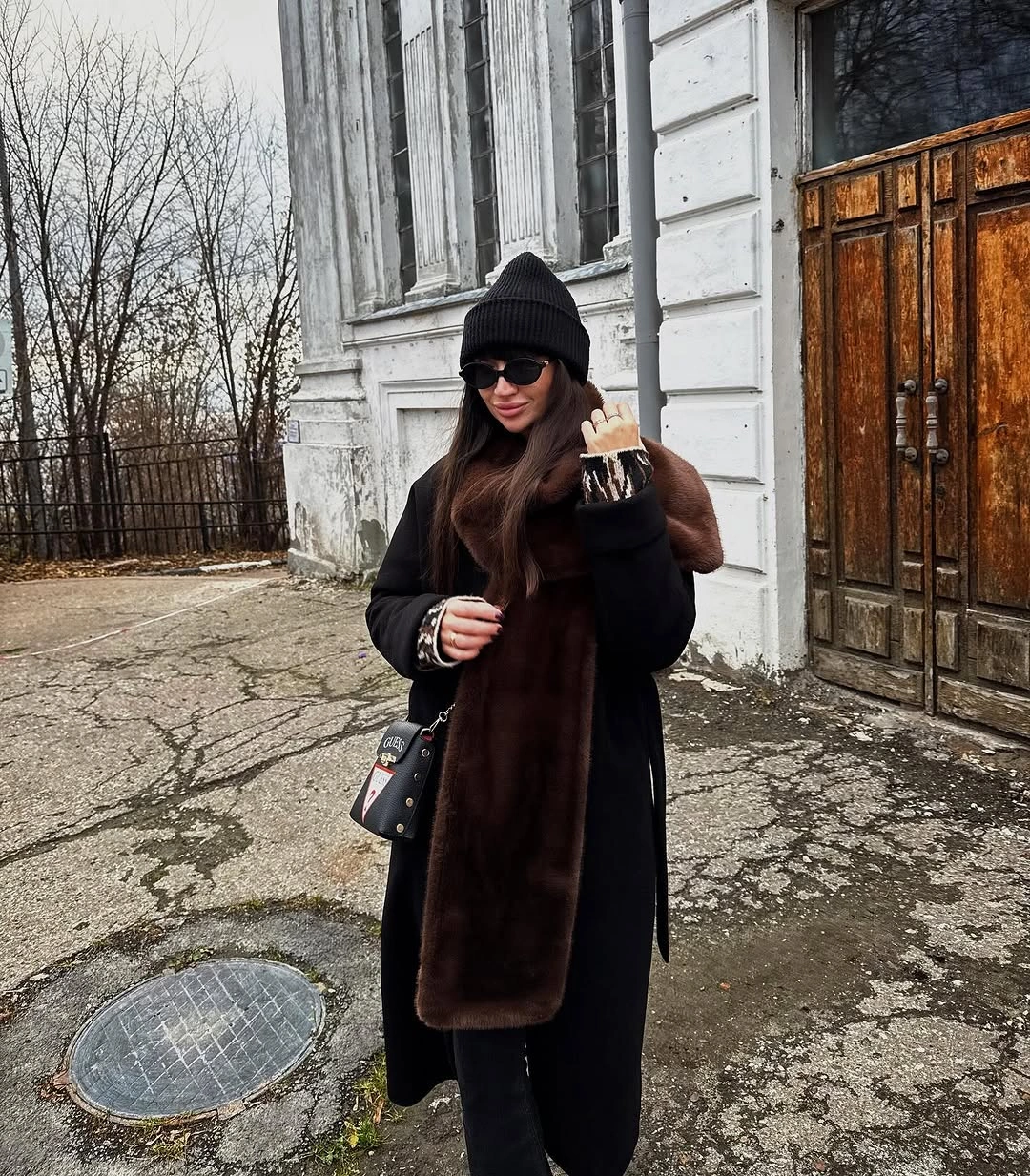 Black coat with beanie, sunglasses and long brown plush-looking scarf