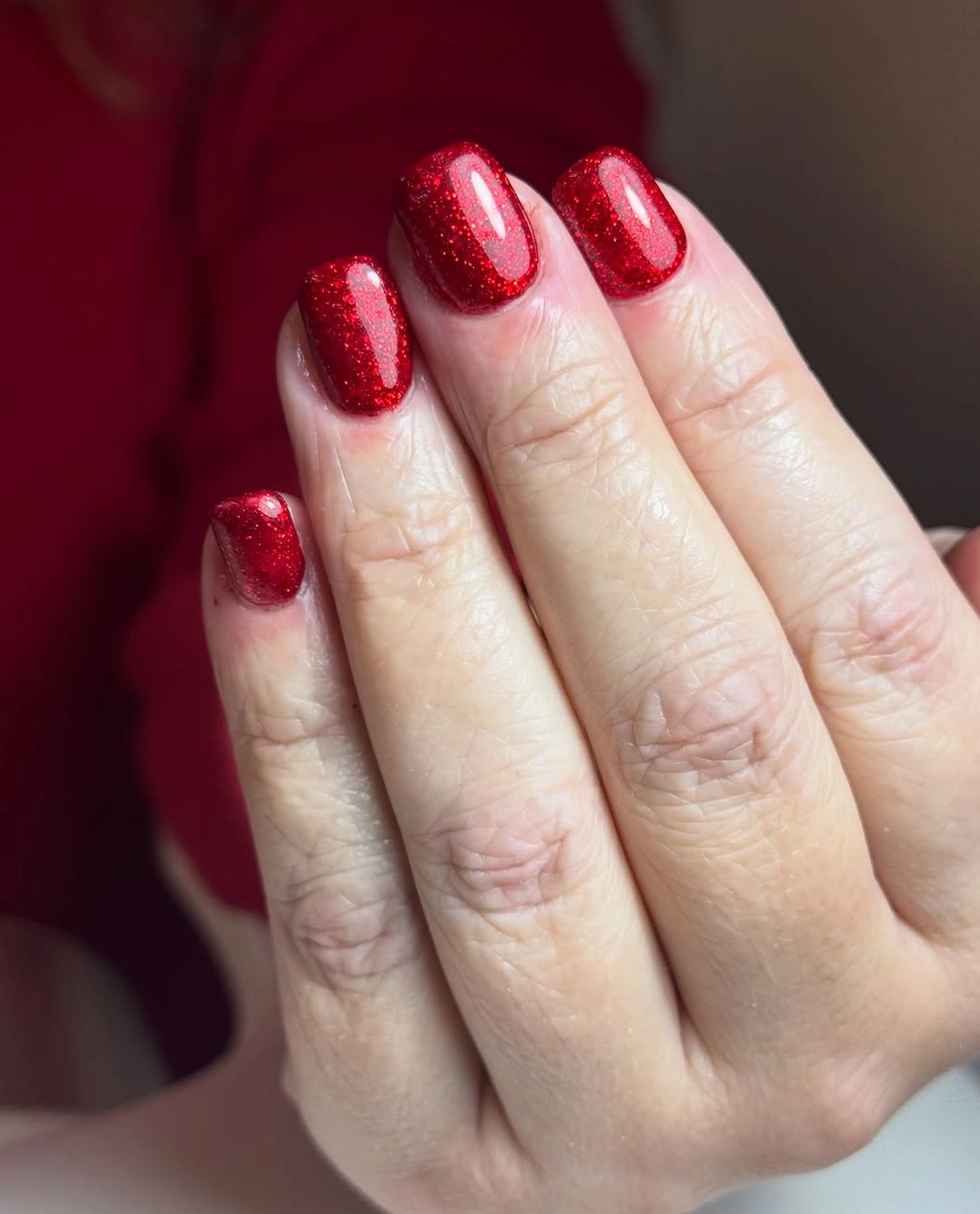 Long almond nails with red shimmer pink accents and white motifs