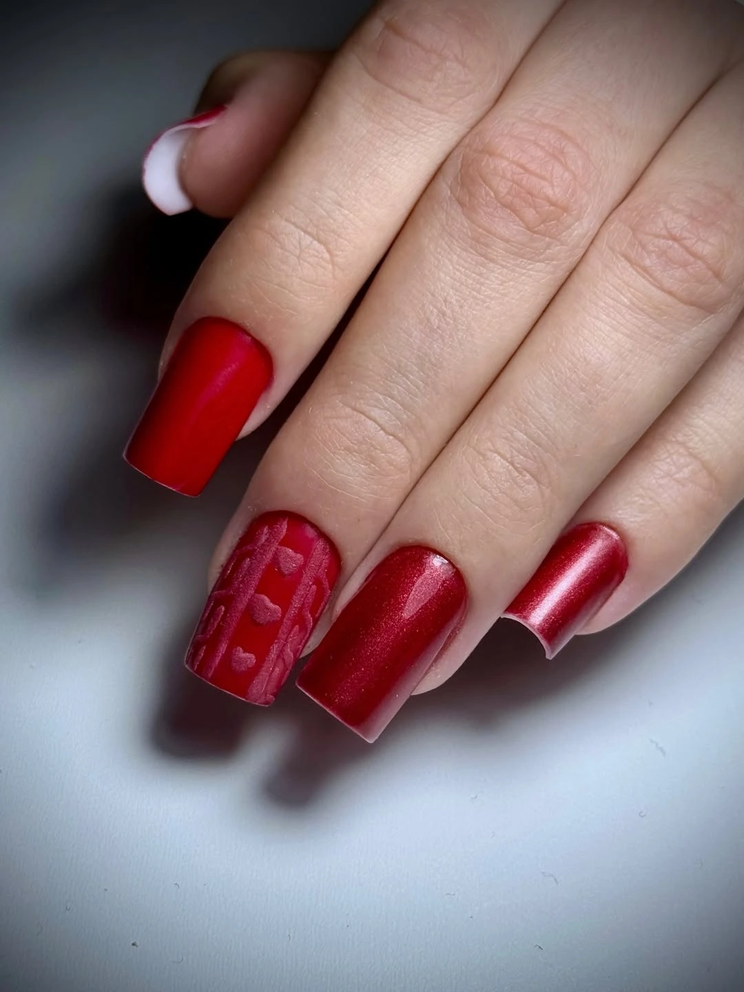 Pale pearly almond nails with red curved lines and bows