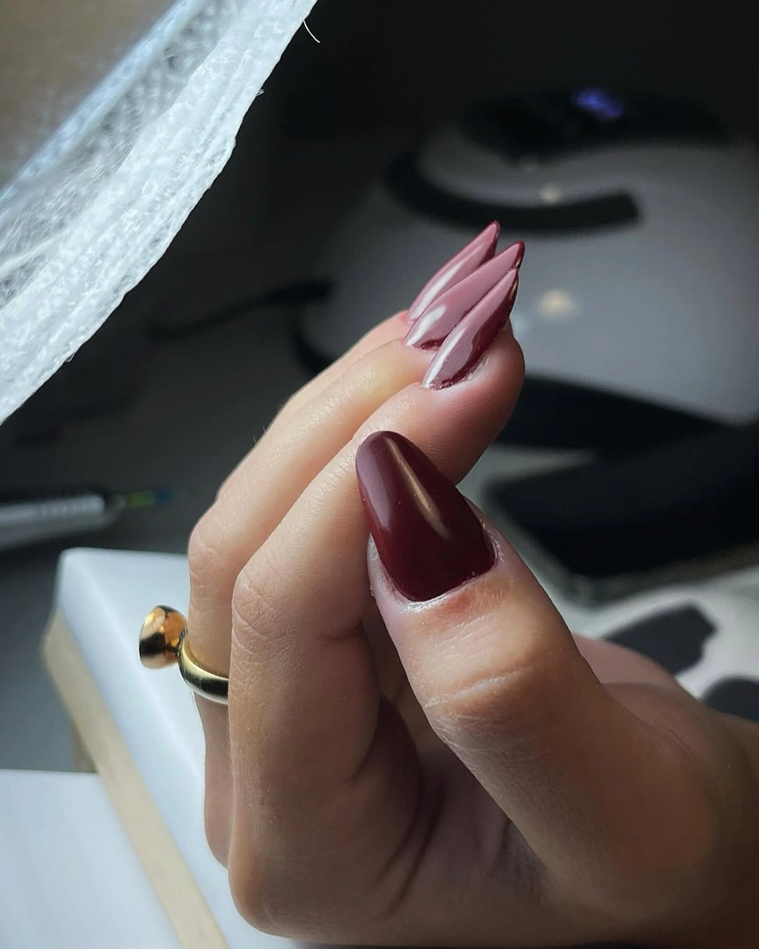 Pointed almond-style nails with burgundy polish and mauve layered accents