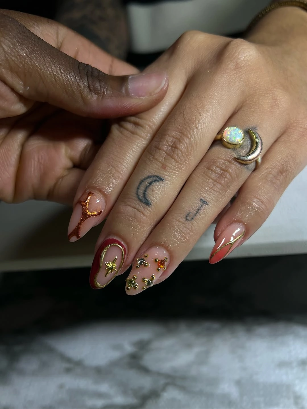 Warm mixed almond nails with gold details and small stone-like accents