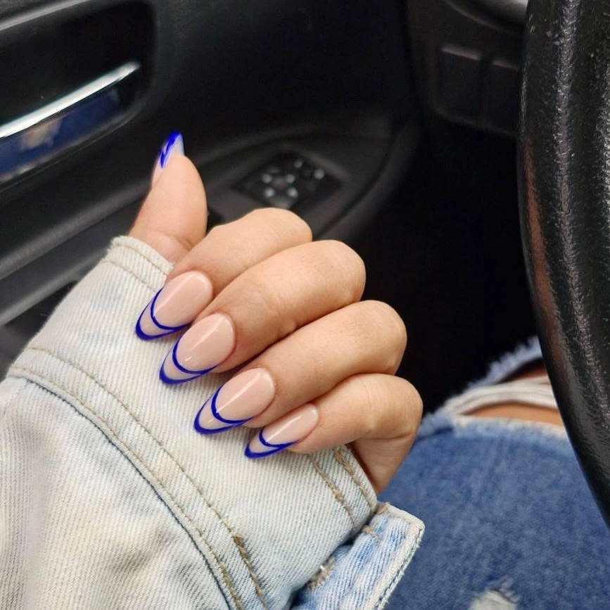 Nude almond nails with cobalt blue curved French outlines