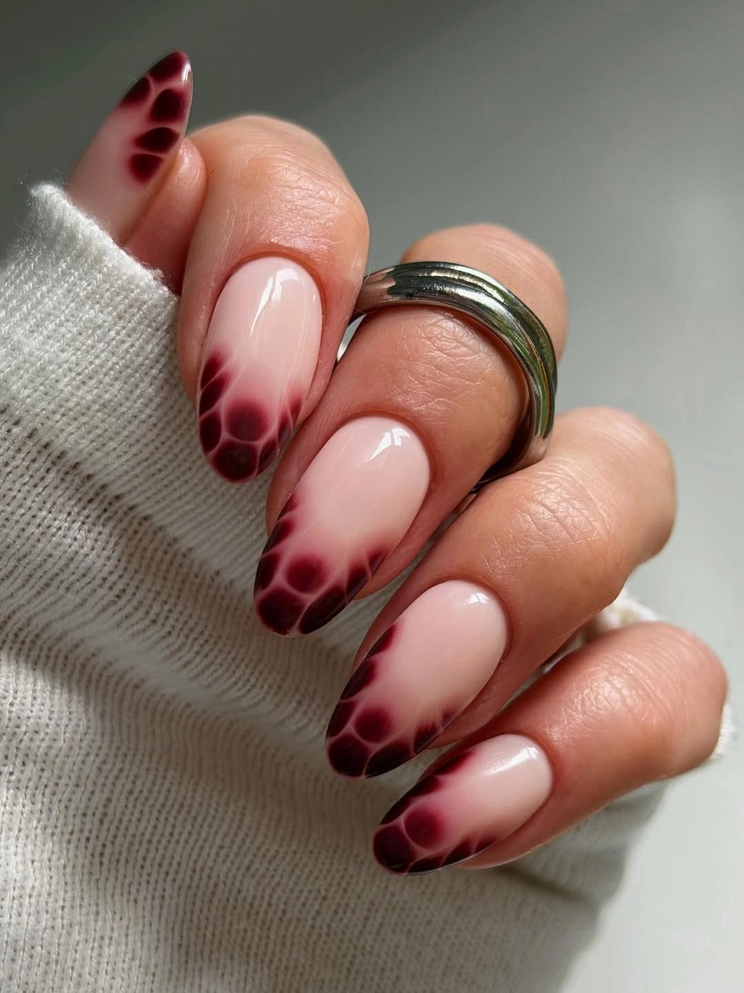 Long nude almond nails with burgundy-brown smoky spotted tips