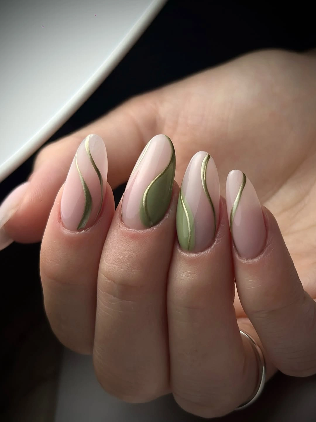 Nude almond nails with olive green panels and gold curved lines