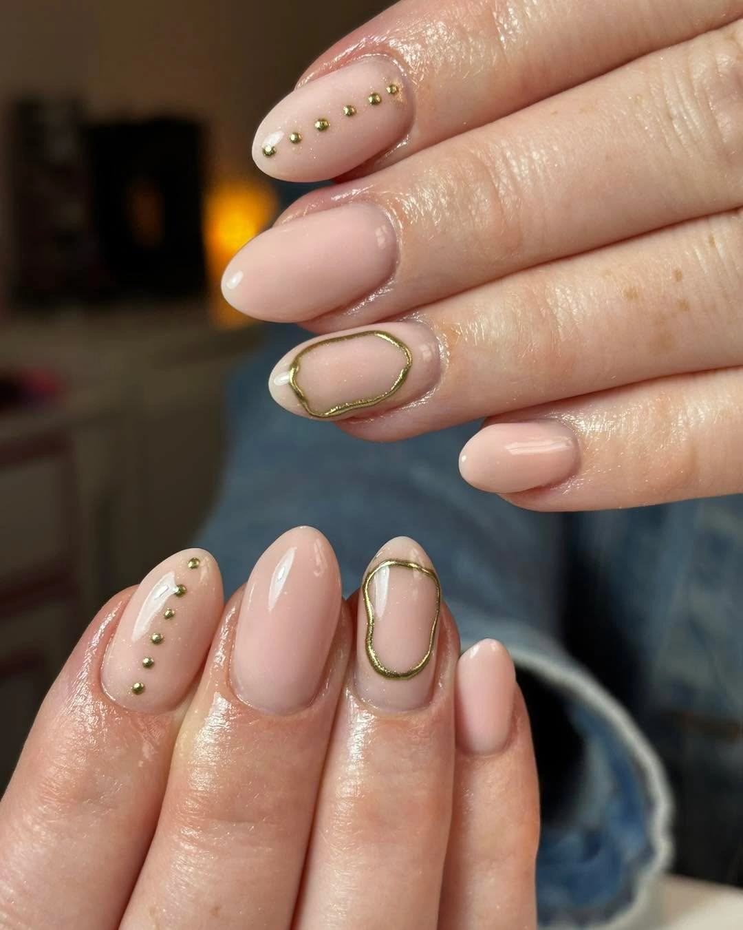 Blush almond nails with gold studs and oval outlines