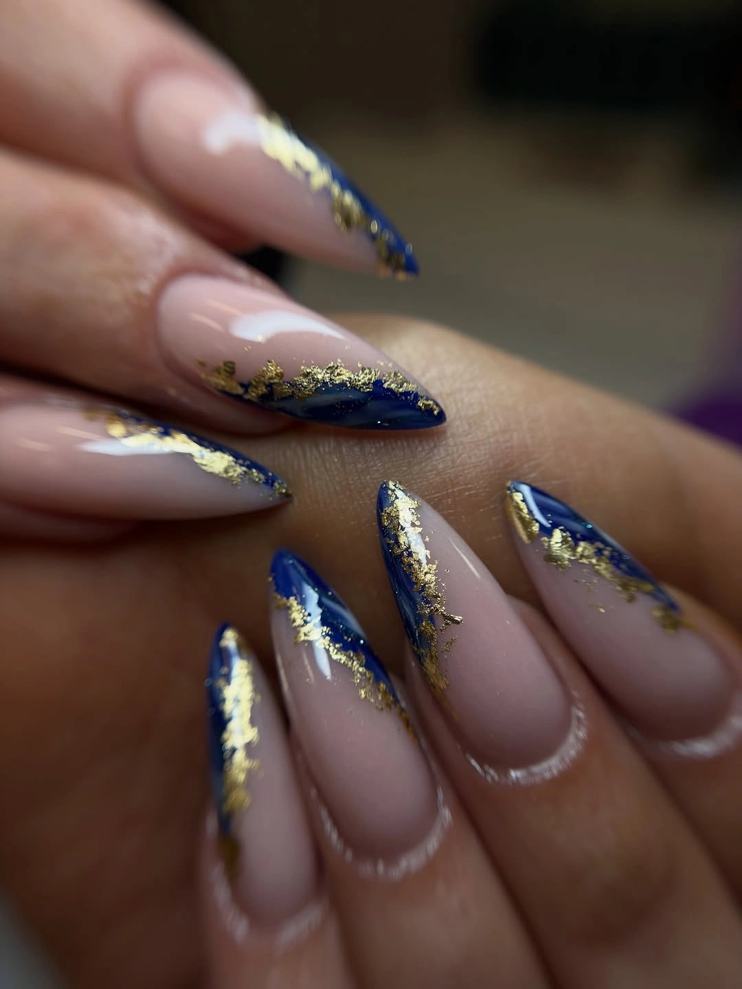 Long nude almond nails with deep blue tips and gold foil