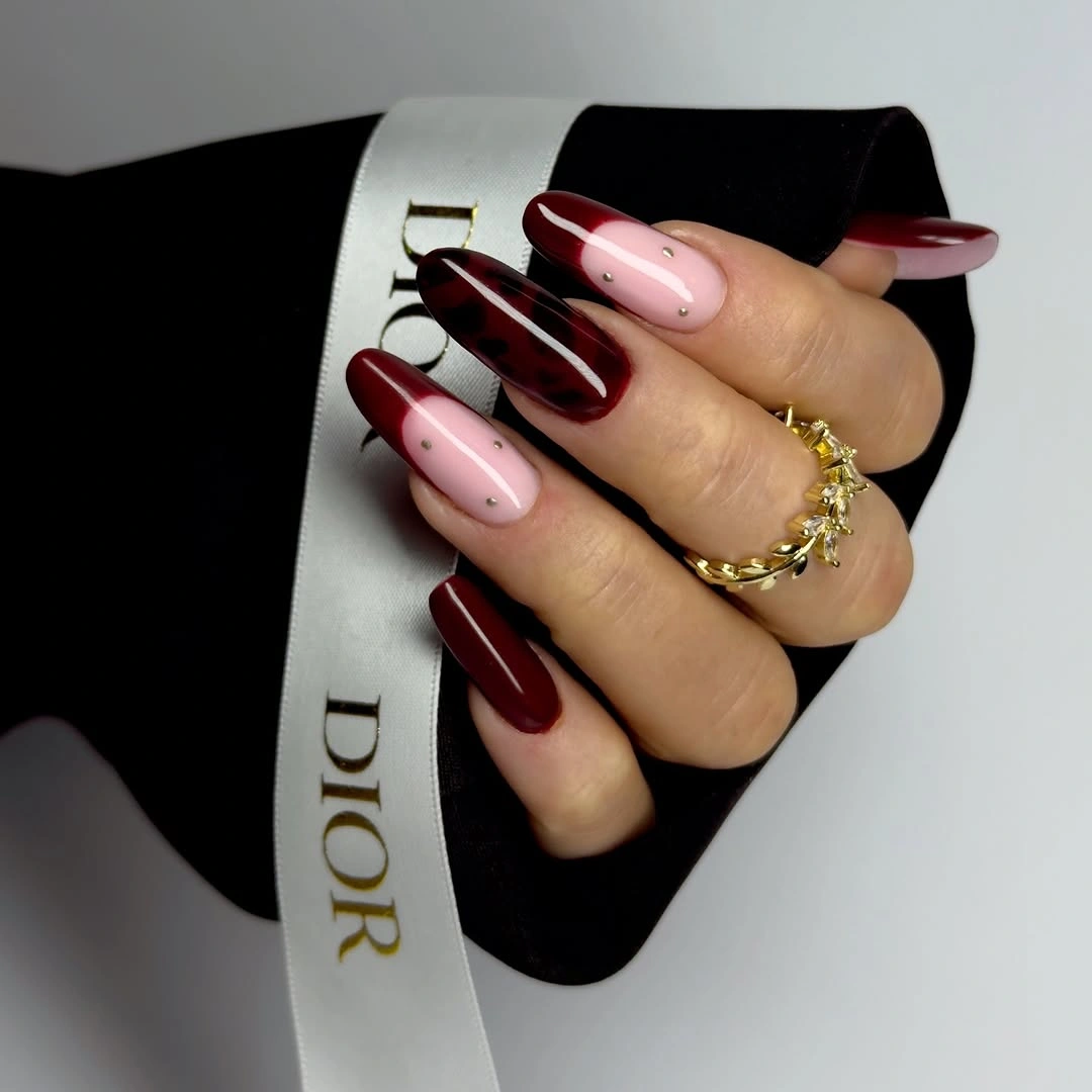 Burgundy almond nails with pale pink accent nails and dots