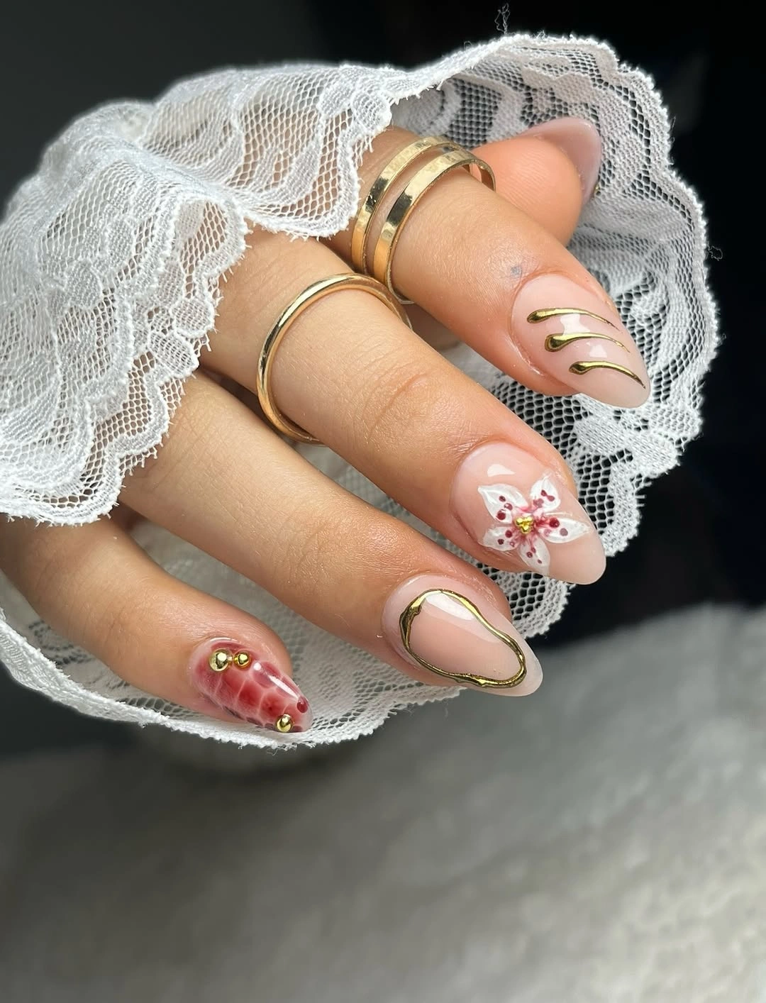 Nude pink almond nails with gold outlines and floral detail
